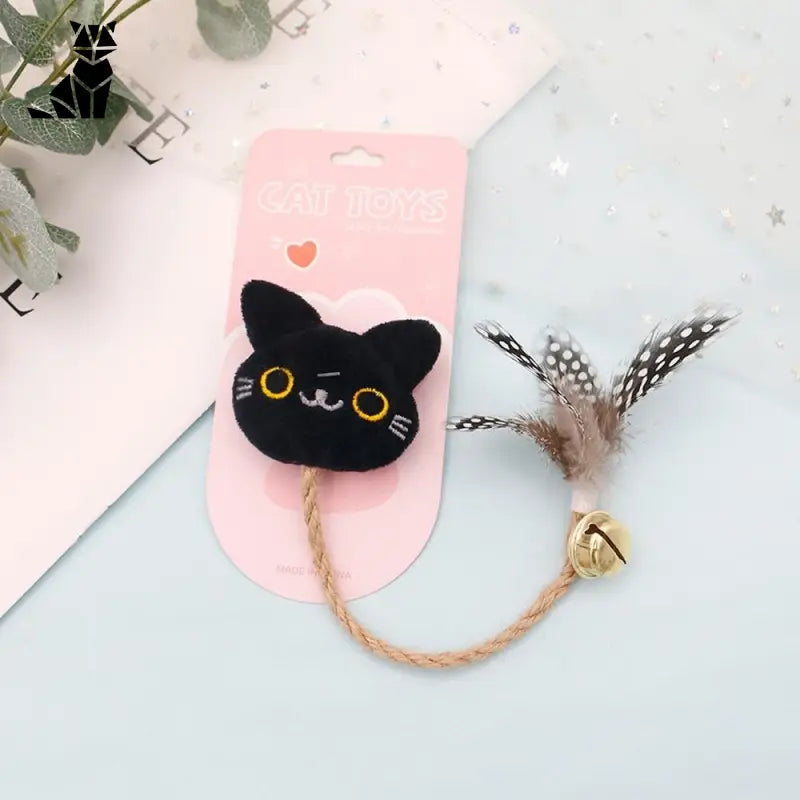 Chat noir aux yeux jaunes et à la médaille rose jouant avec un jouet à mâcher pour chats, plume et menthe