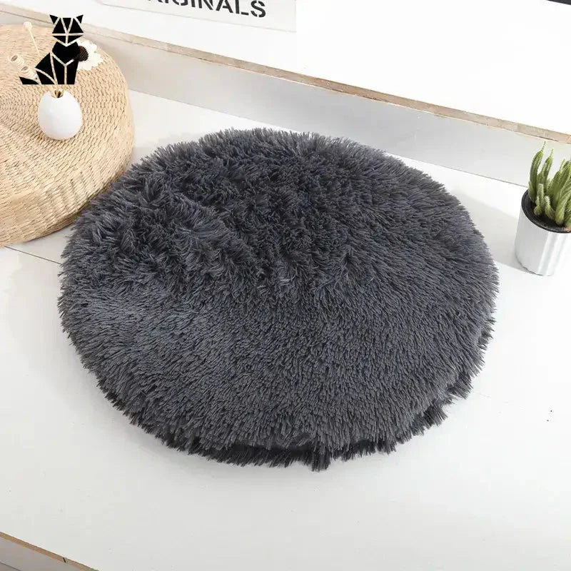 Lit rond pour petits animaux, tapis en peau de mouton gris sur table blanche